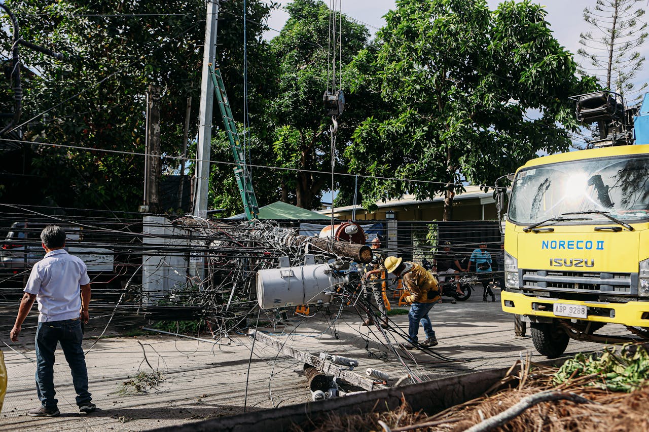 Team of workers in hard hats repairing electrical lines from a fallen pole after an accident.